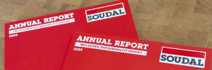 Red annual report booklets on a wooden floor, featuring bold white title text and the SOUDAL logo.